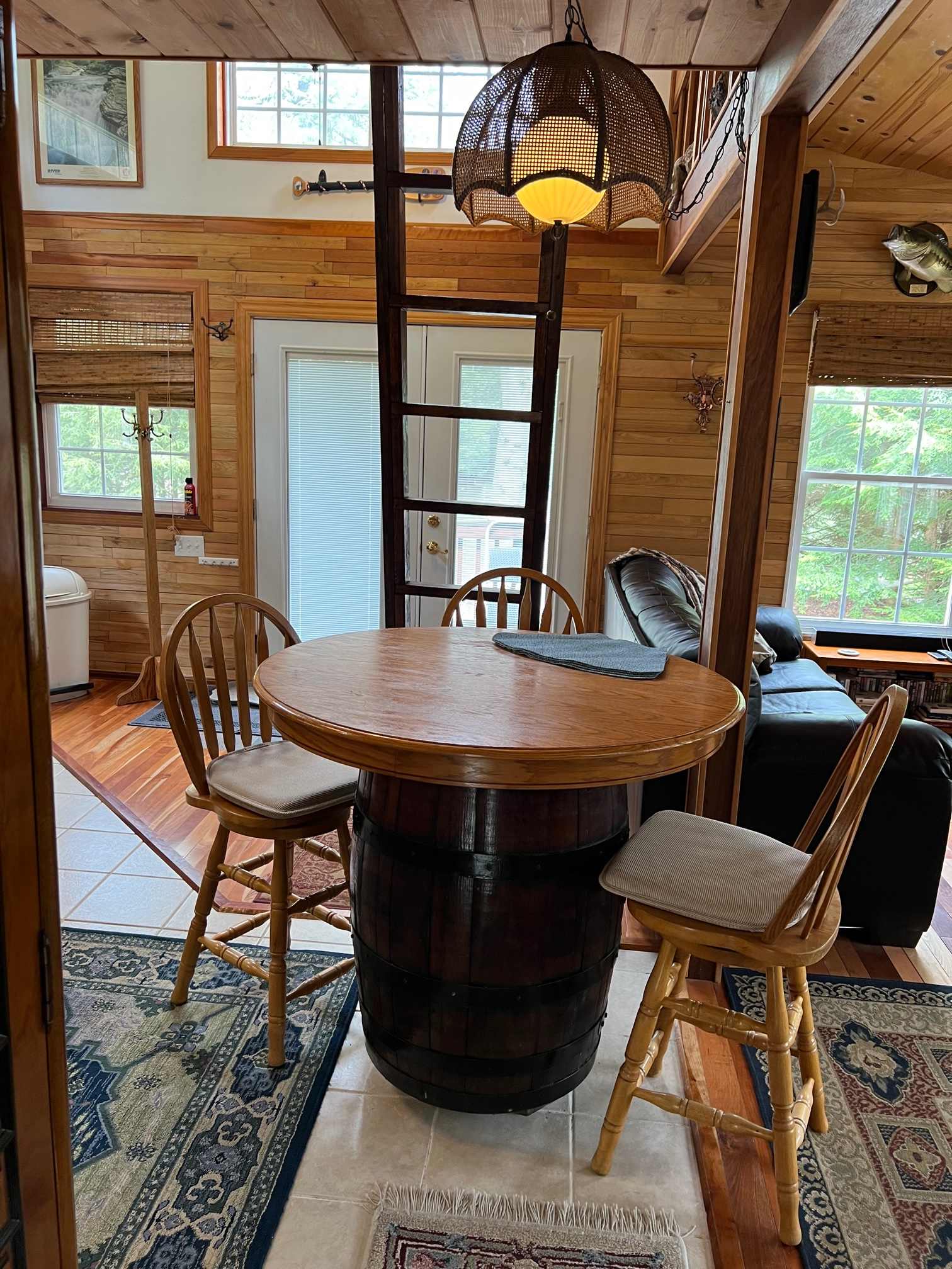 Open area showing table, chairs, ladder to sleeping loft, sleeping couch and front door to outside.